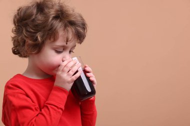 Küçük çocuk kahverengi arka planda taze nar suyu içiyor. Metin için boşluk