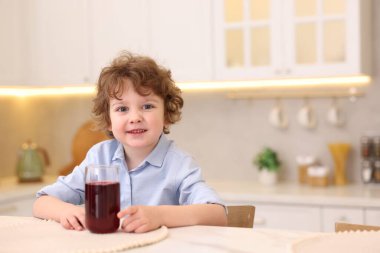 Mutfaktaki masada taze nar suyu olan küçük bir çocuk. Metin için boşluk