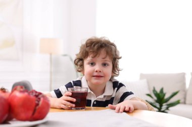 İçerideki masada taze nar suyu olan küçük bir çocuk.