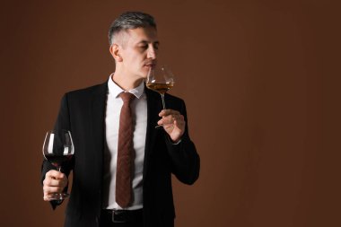 Profesyonel şarap garsonu kahverengi arka planda şarap tadıyor, metin için yer var.
