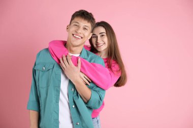 Mutlu çift pembe arka planda birbirine sarılıyor, mesaj için yer var.