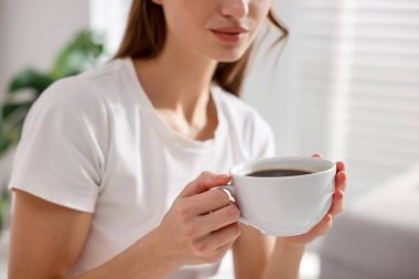 Evde bir fincan aromalı kahveli kadın, yakın plan.