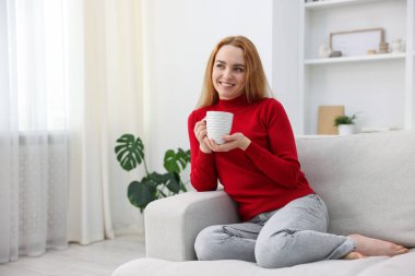 Evdeki kanepede bir fincan aromatik kahveyle güzel bir kadın. Metin için boşluk