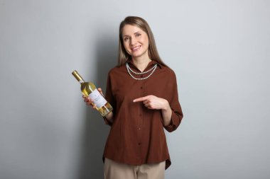 Açık gri arka planda beyaz şarap şişesi olan profesyonel şarap garsonu.