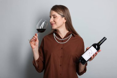 Profesyonel şarap garsonu açık gri arka planda şarap tadıyor.