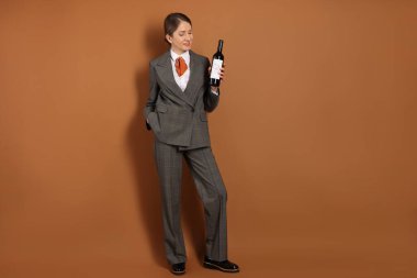 Kahverengi arka planda şarap şişesi olan profesyonel şarap garsonu. Metin için boşluk