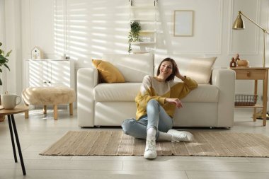 Kadın evinde koltuğun yanında dinleniyor, mesaj için yer var.