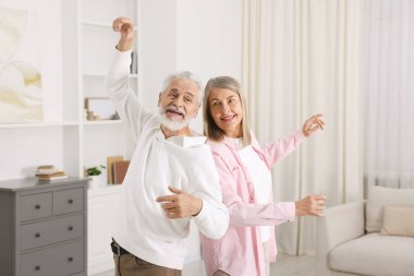 Mutlu yaşlı çift evde dans ediyor.