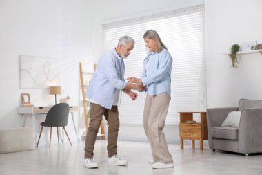 Mutlu yaşlı çift evde dans ediyor.