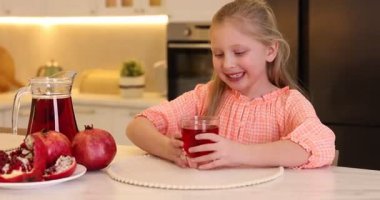 Küçük kız içeride taze nar suyu içiyor.