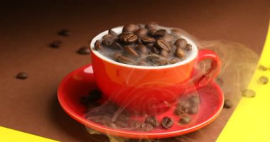 Aromatik kahve çekirdekli fincan ve renkli arka planda buhar, yakın plan.