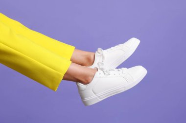 Mor arka planda şık beyaz ayakkabılar giyen kadın, yakın plan.