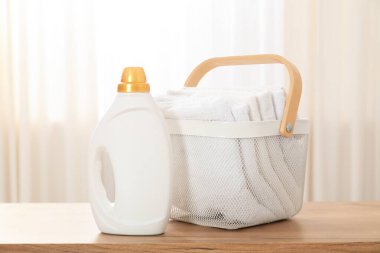 İçerideki ahşap masada havlu ve deterjan dolu çamaşır sepeti.