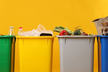 Çöp tenekeleri turuncu arka planda, yakın plan. Atık sıralama