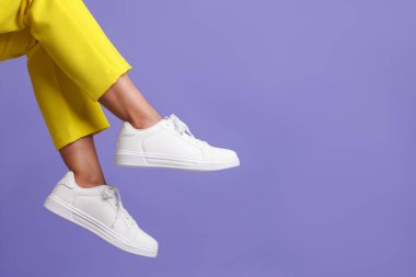 Violet 'in arka planında şık beyaz ayakkabılar giyen bir kadın, yakın plan. Metin için boşluk