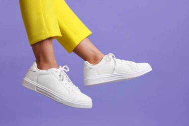 Violet 'in arka planında şık beyaz ayakkabılar giyen bir kadın, yakın plan. Metin için boşluk