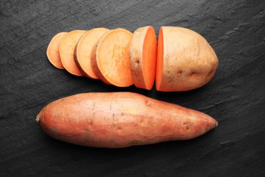 Tatlı patatesleri koyu dokulu masada, düz bir şekilde.