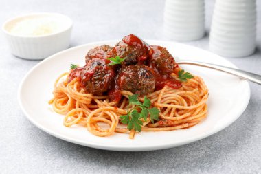 Açık gri masada servis edilen köfteli lezzetli makarna, yakın plan.