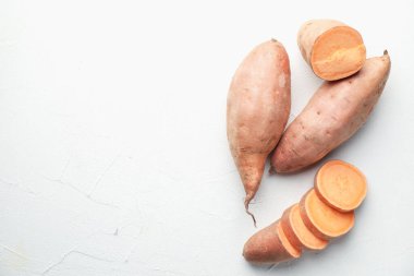 Tam ve çiğ patatesleri beyaz masada düz bir şekilde dilimleyin. Metin için boşluk