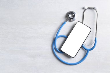 Sağlığınıza. Akıllı telefon ve steteskop ışık desenli masa, üst manzara. Metin için boşluk