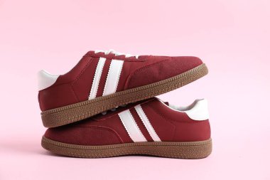 Pembe arka planda şık bir çift spor ayakkabı, yakın plan.