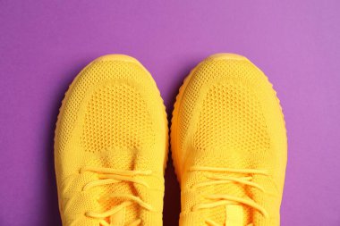 Mor arka planda bir çift şık spor ayakkabı, üst görünüm.