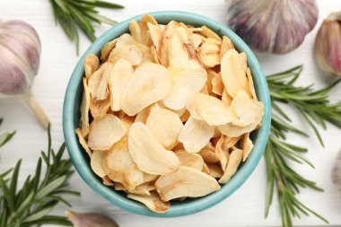 Kasede kurutulmuş sarımsak taneleri, taze sebzeler ve beyaz ahşap masada biberiye, düz uzanmış.