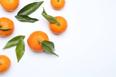 Beyaz arka planda olgun mandalinalar ve yeşil yapraklar. Metin için boşluk