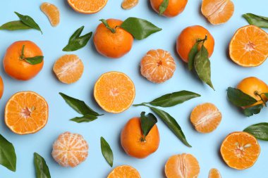 Taze, sulu mandalinalar ve açık mavi arka planda yeşil yapraklar.