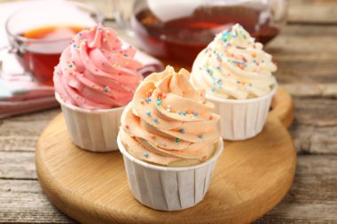 Tahta masaya serpiştirilmiş lezzetli kekler ve çay, yakın plan.