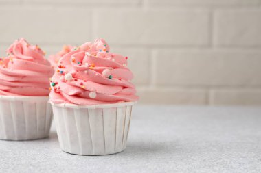 Açık gri masaya serpiştirilmiş enfes kekler, yakın plan. Metin için boşluk