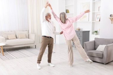 Mutlu yaşlı çift evde dans ediyor.