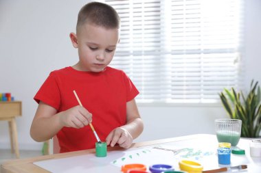 Masada fırçayla resim yapan şirin bir çocuk. Metin için boşluk