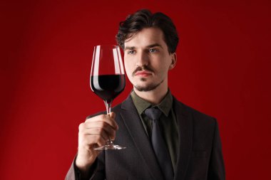 Kırmızı arka planda şarap kadehi olan profesyonel şarap garsonu.