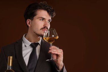 Profesyonel şarap garsonu kahverengi arka planda beyaz şarap tadıyor. Metin için boşluk