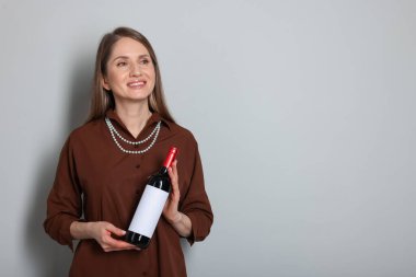 Açık gri arka planda şarap şişesi olan profesyonel şarap garsonu. Metin için boşluk