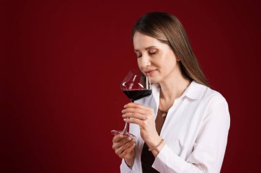 Profesyonel şarap garsonu kırmızı arka planda şarap tadıyor. Metin için boşluk