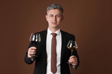 Kahverengi arka planda şarap kadehleri olan profesyonel şarap garsonu.