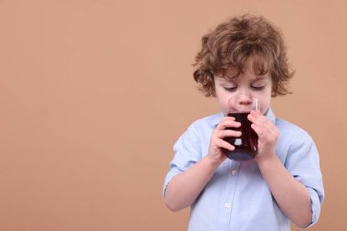 Küçük çocuk kahverengi arka planda taze nar suyu içiyor. Metin için boşluk