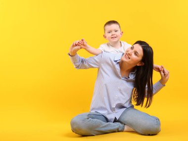 Sarı arka planda oğlunun yanında mutlu bir anne.