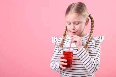 Küçük kız pembe arka planda taze nar suyu içiyor. Metin için boşluk