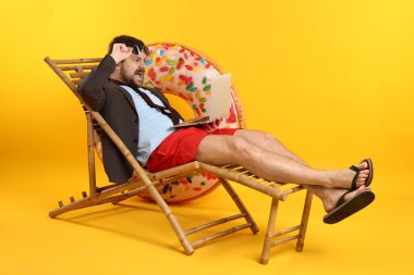 Turuncu arka planda dizüstü bilgisayarı olan bir ofis çalışanı.