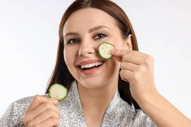 Beyaz arka planda salatalık dilimleri olan bir kadın.