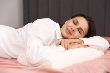 Evde ortopedik yastıkla uyuyan genç bir kadın. Sağlıklı duruş