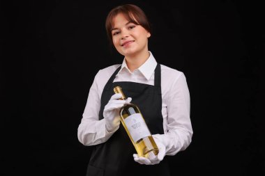 Siyah arka planda beyaz şarap şişesi olan profesyonel şarap garsonu.