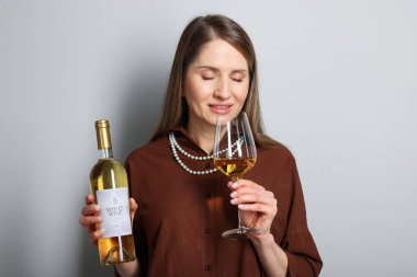 Açık gri arka planda cam ve bir şişe beyaz şarap ile profesyonel şarap garsonu.