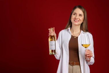 Kırmızı arka planda şişe ve bir bardak beyaz şarap olan profesyonel şarap garsonu. Metin için boşluk