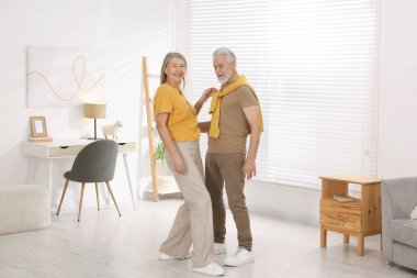 Mutlu yaşlı çift evde dans ediyor.