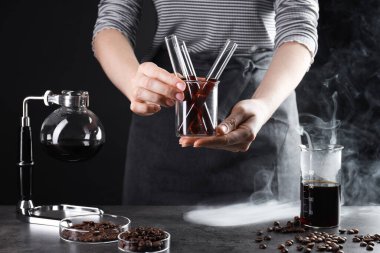 Elinde cam kahve tüpleri, fasulye ve vakumlu kahve makinesi olan kadın, yakın plan.