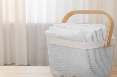 Ahşap masanın üzerinde havlular olan çamaşır sepeti, yakın plan. Metin için boşluk